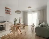 Jasna kuchnia z wyspą i okrągłym stołem. Nad stołem wisi lampa na linie, która tworzy przytulną atmosferę.