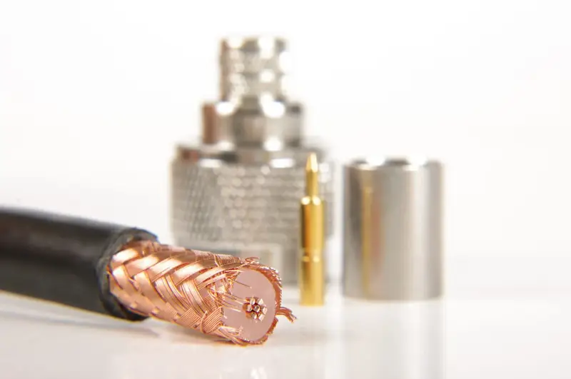 Przewód ekranowany z miedzianym oplotem, obok złoty pin i metalowe złącza.